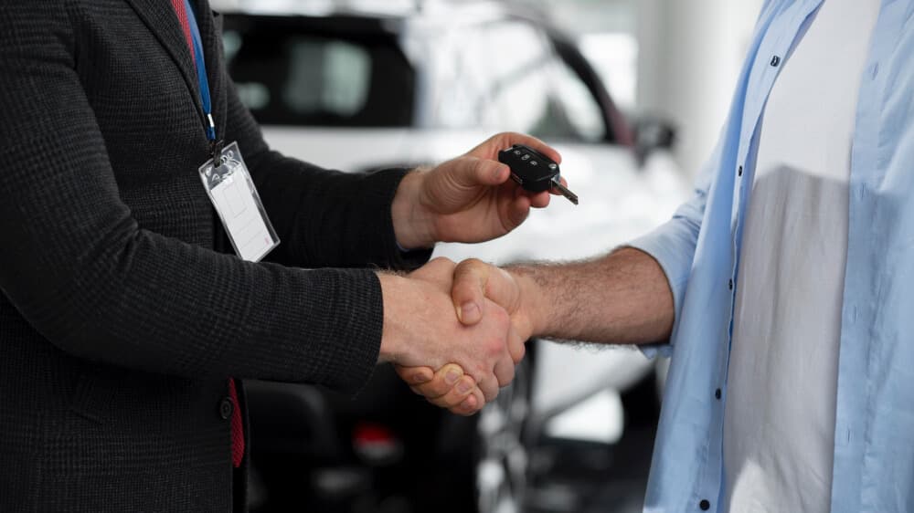 Car keys being handed over during a vehicle purchase, symbolizing the final step in buying a car in Dubai.