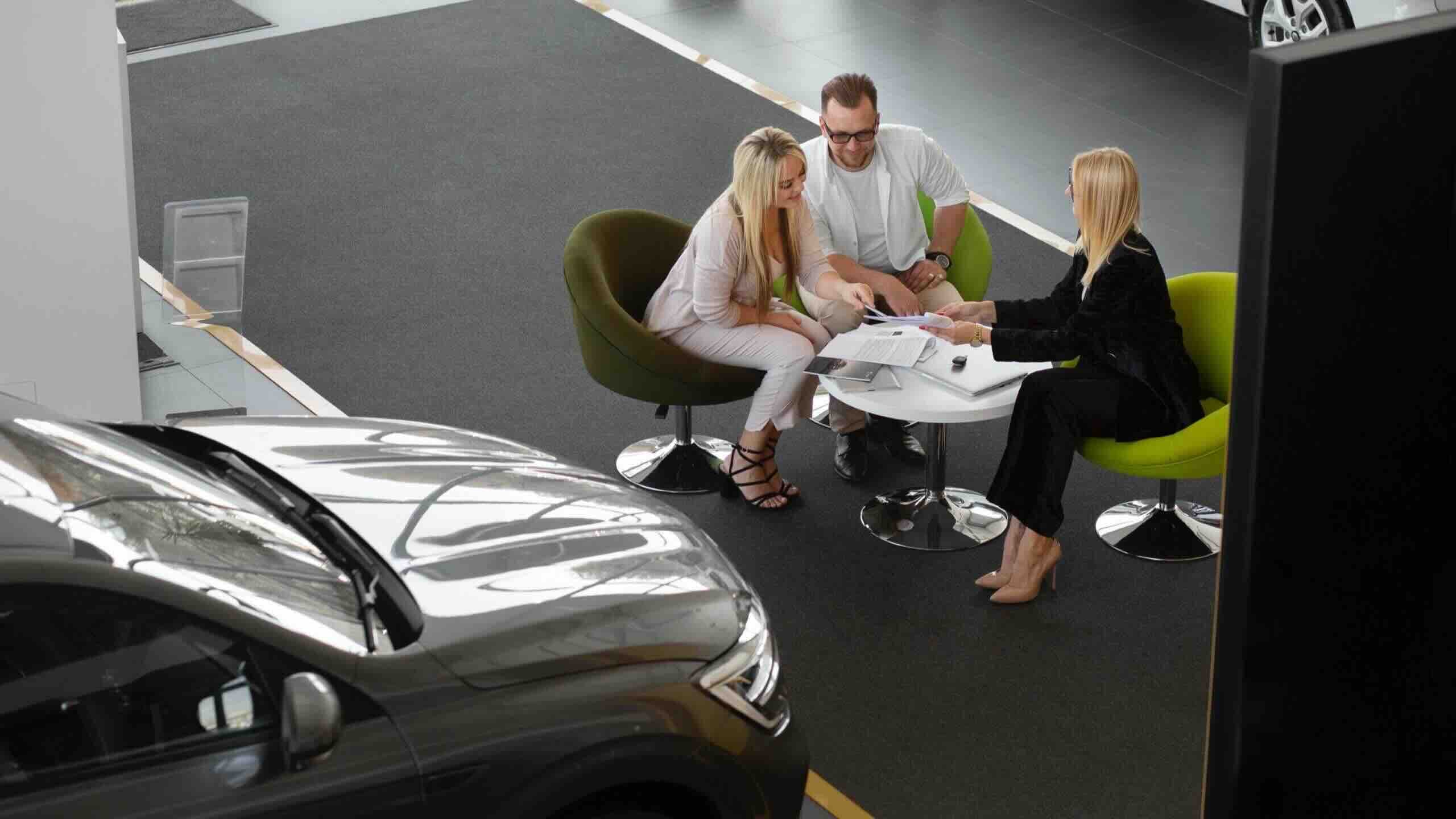 A couple discussing car finance UAE options with a sales advisor inside a dealership.